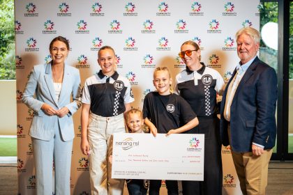 Erin Lockwood and young BMX riders from her racing squad proudly hold their Community Fund cheque from Nerang RSL on Donation Day, smiling in team gear.
