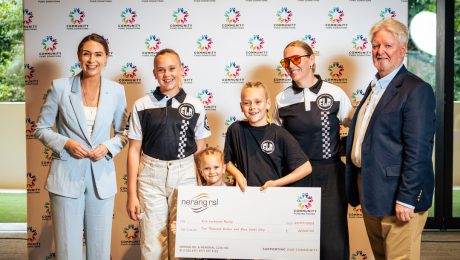 Erin Lockwood and young BMX riders from her racing squad proudly hold their Community Fund cheque from Nerang RSL on Donation Day, smiling in team gear.
